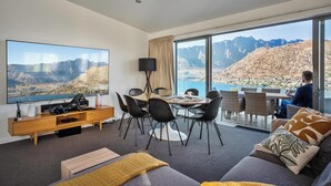 Ein modernes Hotelzimmer mit großem Fernseher, Essbereich und Bergblick.