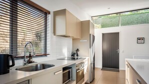 Eine moderne Küche mit Edelstahlgeräten, einer doppelten Spüle und einem großen Fenster mit Jalousien.