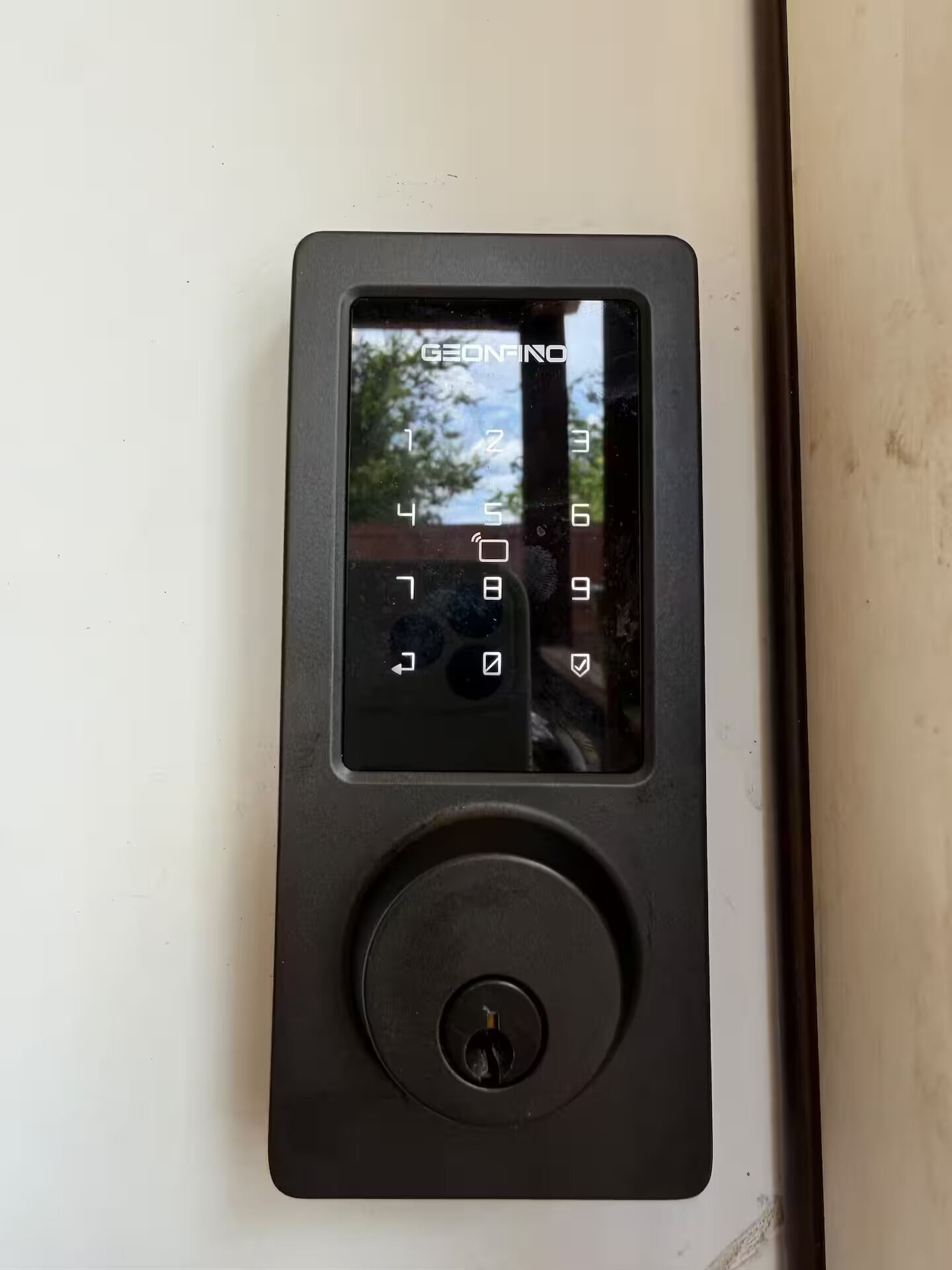 A GEONINO door lock with a keypad and a round button.