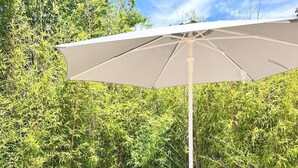 An outdoor patio with a table, chairs, and a large umbrella. - Gordes - Luberon: Charming house with private pool (exclusive access) (Gordes)