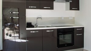 A modern kitchen with black cabinets, a stainless steel sink, and a built-in oven. - Gordes - Luberon: Charming house with private pool (exclusive access) (Gordes)