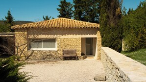 A stone building with a tiled roof, a bench, and a gravel driveway. - Gordes - Luberon: Charming house with private pool (exclusive access) (Gordes)
