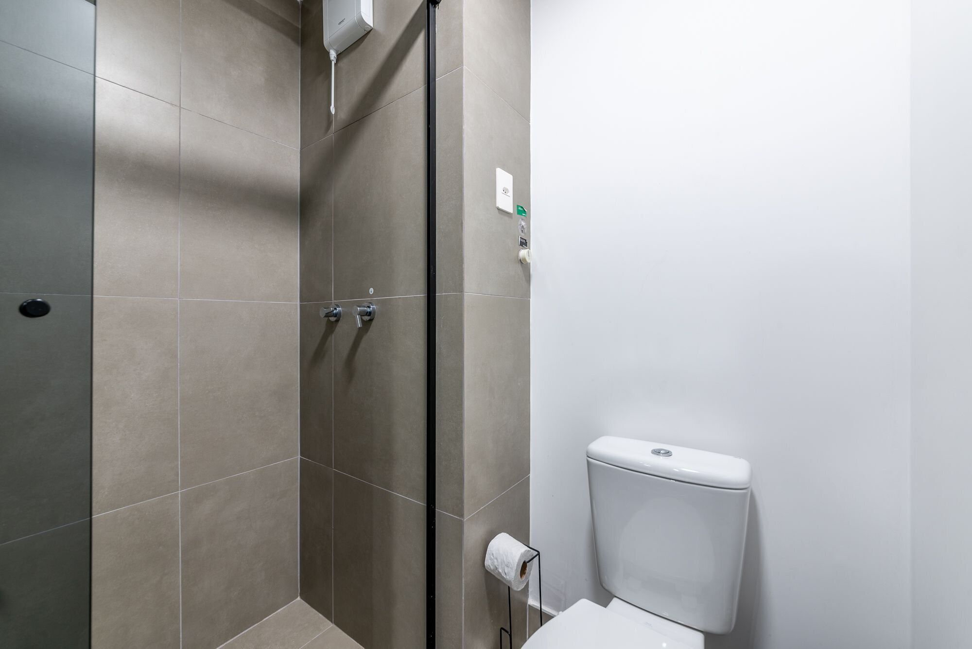 A bathroom with a toilet, a shower with a glass door, and a towel rack.