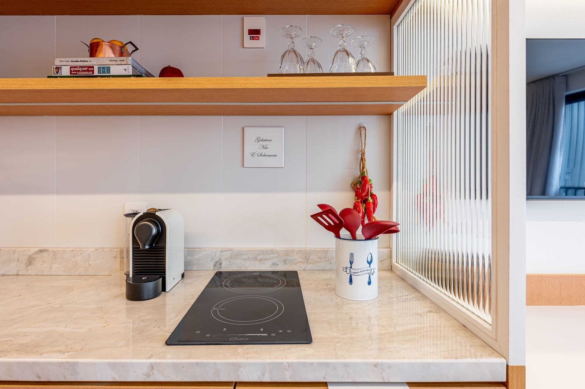 A kitchen with a built-in stove, a coffee machine, and a spice rack.