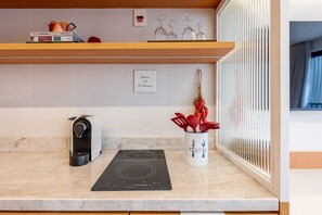 A kitchen with a built-in stove, a coffee machine, and a spice rack. - GO24 by LikeHome (Porto Alegre)