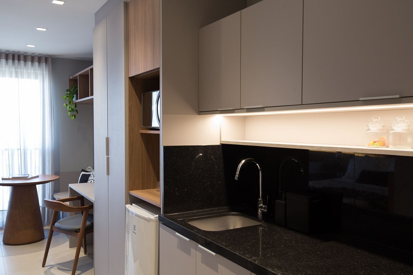 A modern kitchen with a black countertop, stainless steel sink, and wooden cabinets.