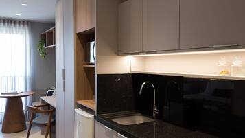 A modern kitchen with a black countertop, stainless steel sink, and wooden cabinets.