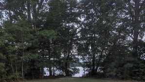 Un foyer avec deux fauteuils Adirondack et une couverture, entouré de sable et d’arbres.