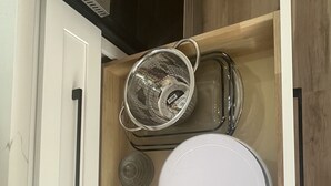 Uma gaveta de cozinha com um escorredor, um ralador e um prato branco.