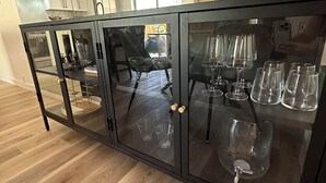 Uma cozinha moderna com armário de vidro preto, piso de madeira e iluminação pendente.