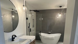 Um banheiro moderno com uma banheira independente, um espelho grande e uma pia com bancada de mármore.