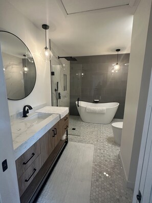 A modern bathroom with a freestanding bathtub, a large mirror, and a vanity with a marble countertop. - Cocoa Beach its Best, Bring FIDO! (Cocoa Beach)