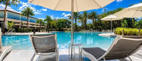 A poolside area with lounge chairs, umbrellas, and a clear blue sky.