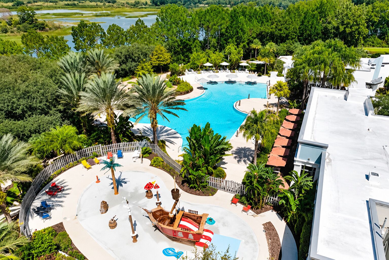 A resort with a large swimming pool, palm trees, and a boat-shaped water feature.