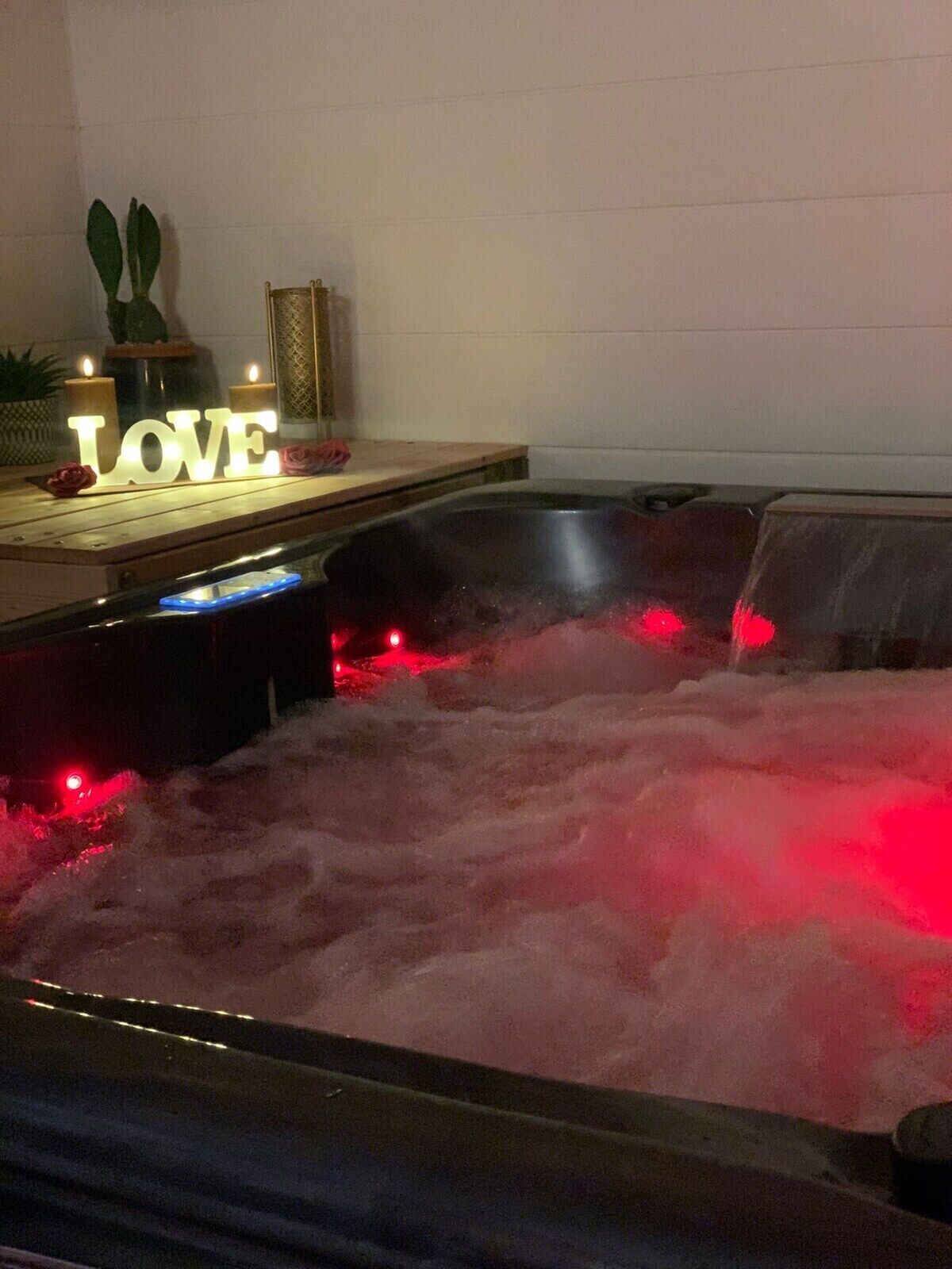 A hot tub with red lighting, a wooden bench, and a 'LOVE' sign.
