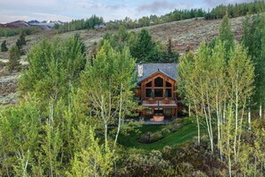 A wooden cabin with a balcony, surrounded by trees and a hilly landscape. - Abode at Sleeping Indian, Jackson Hole, 5 suites (Jackson)