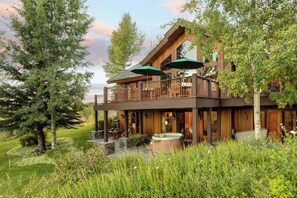 A two-story log cabin with a balcony, outdoor seating, and a hot tub. - Abode at Sleeping Indian, Jackson Hole, 5 suites (Jackson)