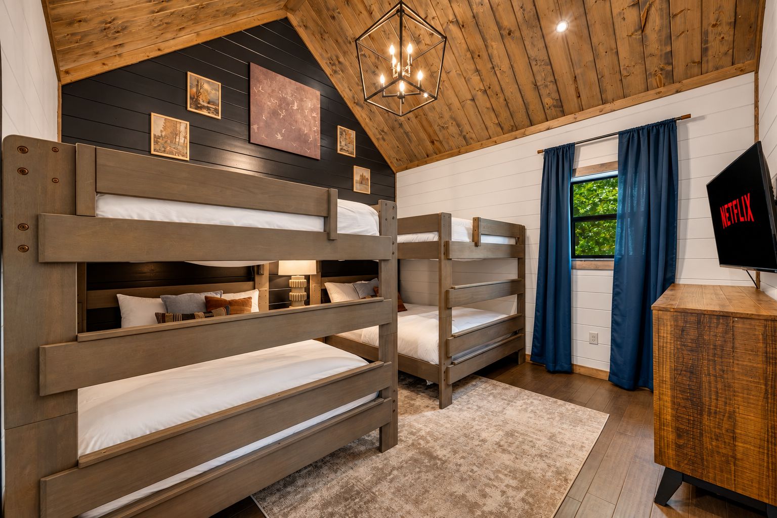 Una habitación con literas, televisión y ventana con cortinas.