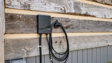 Un cuadro eléctrico exterior fijado a una pared de madera con un cable negro conectado.