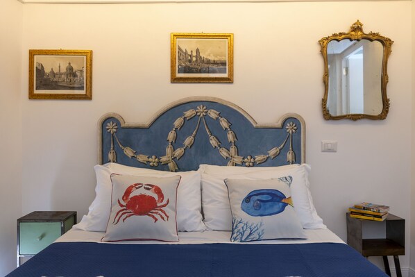 A bed with a blue headboard, two pillows with marine-themed designs, and two framed pictures on the wall. - Banchi Fontana - Castel Sant Angelo (Rome)