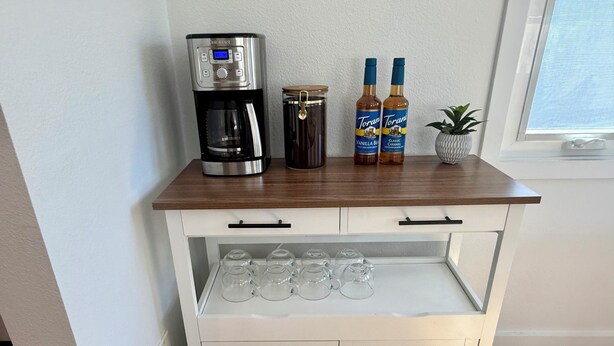 A white wooden cart with a coffee maker, two bottles of Torani syrup, and a jar of honey. - Huntington Beach Surf Shack - Surf City, U.S.A. - Legal Rental (Huntington Beach)