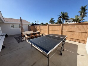 A backyard with a ping pong table, a sofa, and a wooden fence. - Huntington Beach Surf Shack - Surf City, U.S.A. - Legal Rental (Huntington Beach)