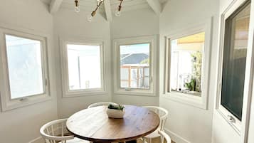 A dining area with a wooden table, white chairs, and a chandelier.