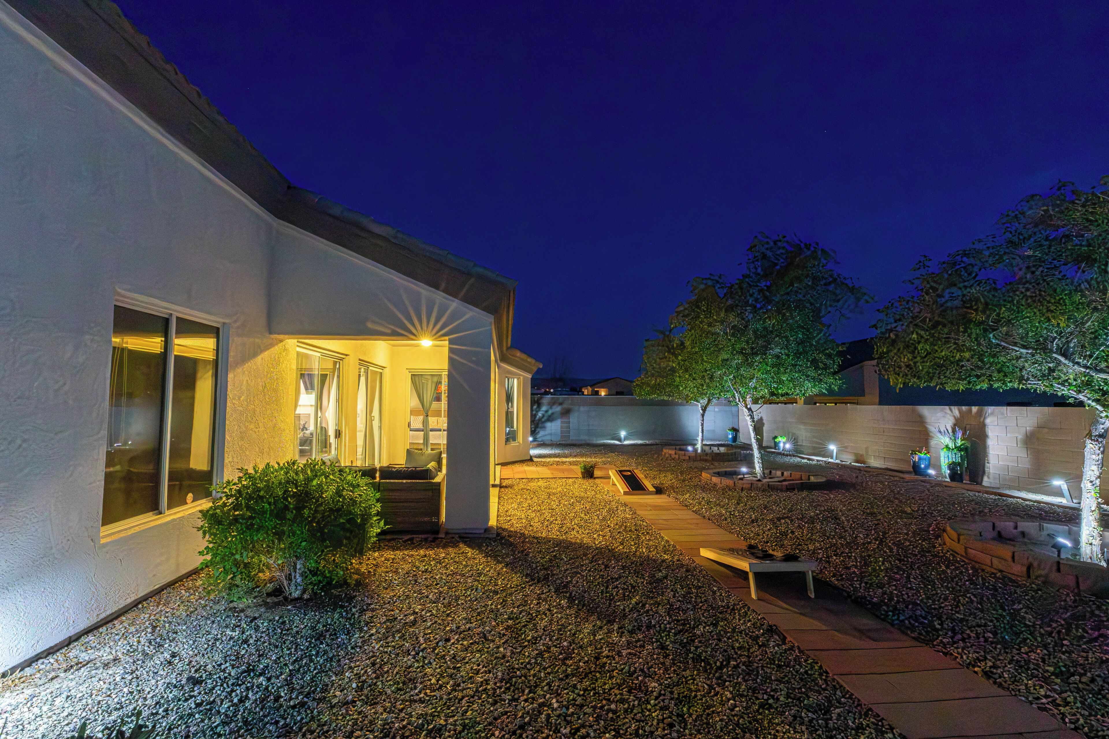A modern house with a patio, a small garden, and a pathway leading to the entrance.