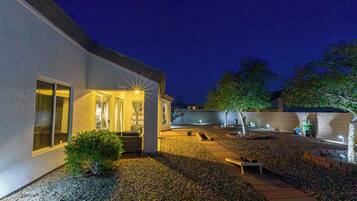 A modern house with a patio, a small garden, and a pathway leading to the entrance.