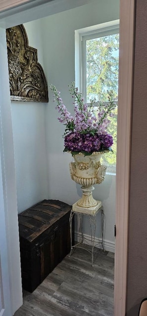 A room with a window, a decorative wall piece, a flower vase, and a wooden chest. - Comfortable 1-bedroom apartment with AC in Hamilton with beautiful views (Hamilton)