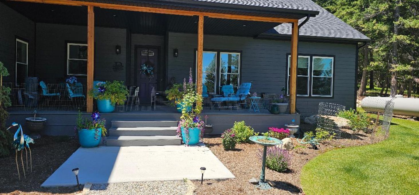 A house with a covered porch, outdoor seating, and potted plants.