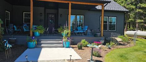 A house with a covered porch, outdoor seating, and potted plants.