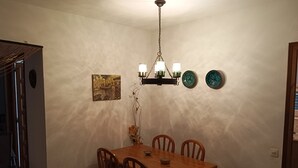 Een eetruimte met een houten tafel en stoelen, een hanglamp en decoratieve borden aan de muur.