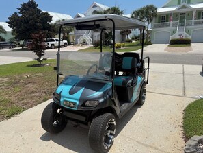 Un carrito de golf estacionado en una entrada de casa.