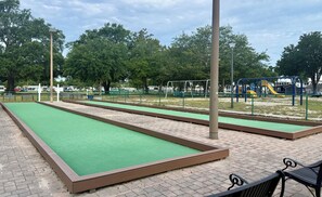 Un parc doté de terrains de croquet recouverts de gazon synthétique, d’une aire de jeux et d’un espace clos avec des bancs.