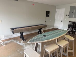 Une pièce équipée d’une table de billard, d’un jeu de fléchettes et de tabourets de bar.