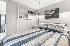 Une chambre à coucher avec un lit, une table de chevet, une étagère avec un panneau, un tableau au mur et une porte.
