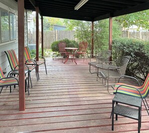A covered patio with a wooden deck, metal chairs, and a table. - Mackey Park Retreat! (Lubbock)