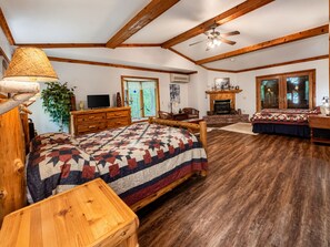 Ein geräumiges Schlafzimmer mit einem großen Bett, einer Holzkommode, einem Schreibtisch und einem Kamin.
