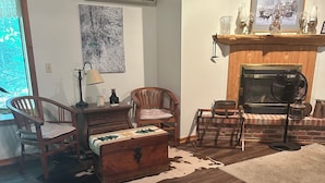 Ein Wohnzimmer mit Kamin, Holzmöbeln, einem Teppich und einem Kuhfellteppich auf dem Boden.