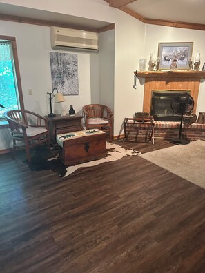 A living room with a fireplace, wooden furniture, a rug, and a cowhide rug on the floor. - Beautiful home, giant windows, sand beach, dock. Premier crystal clear lake. (Bemidji)