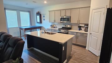 A modern kitchen with a central island, stainless steel appliances, and a dining area with leather chairs.