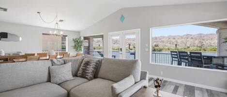 A modern living room with a sectional sofa, dining area, and a view of the mountains.