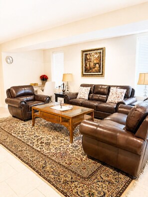 A living room with a brown leather sofa set, a wooden coffee table, and a patterned rug.