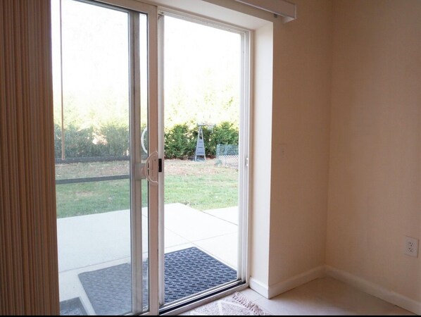 Una habitación con puerta de vidrio corrediza que da a un patio con felpudo.