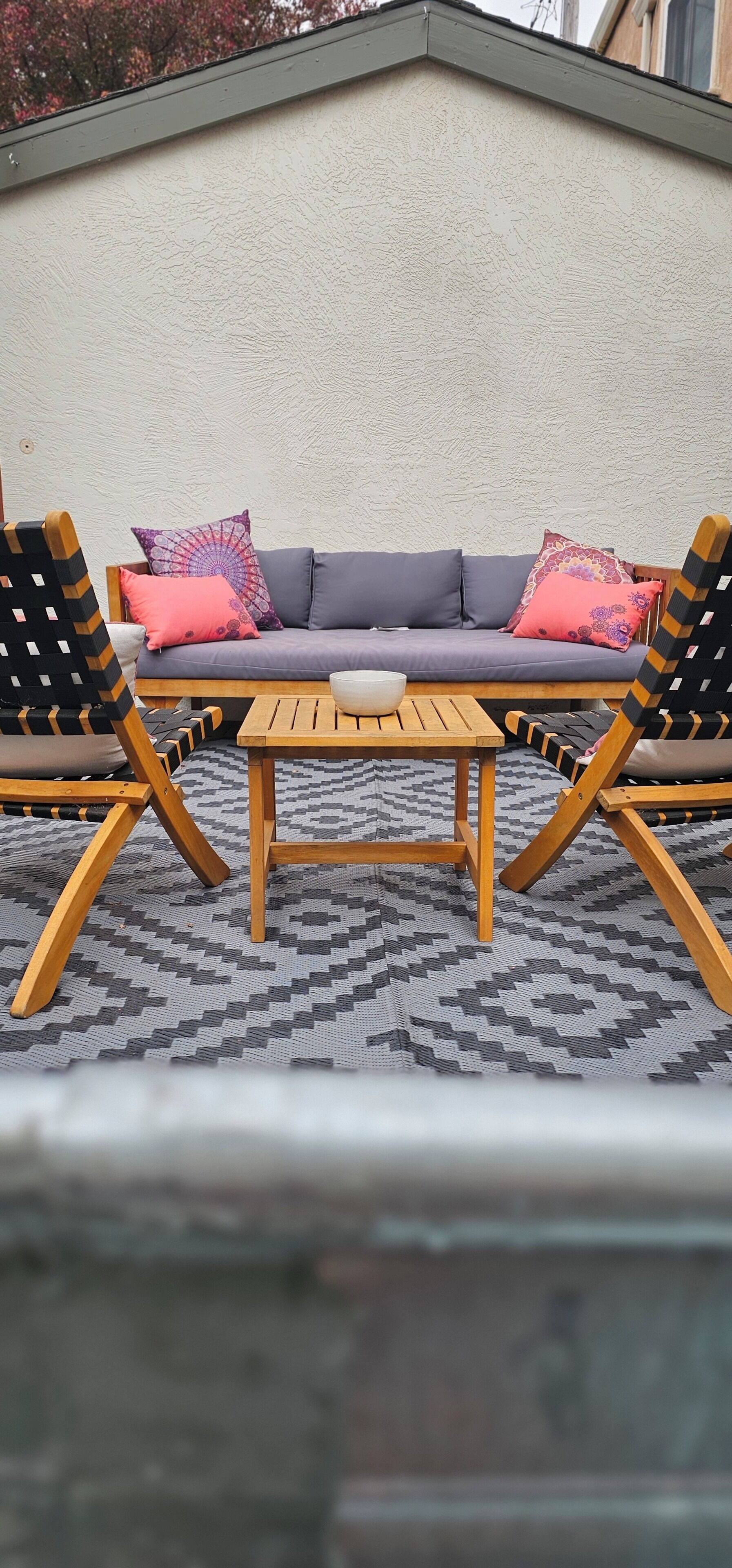 Un divano con cuscini decorati, due sedie di legno e un tavolino.
