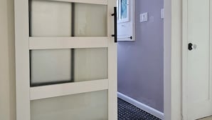 A room with a sliding door, carpeted floor, and a door with a lock. - Charming 1920s Westbrae Berkeley Cottage with Soaking Tub! Walk to BART & Parks (Berkeley)
