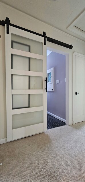 A room with a sliding door, carpeted floor, and a door with a lock.