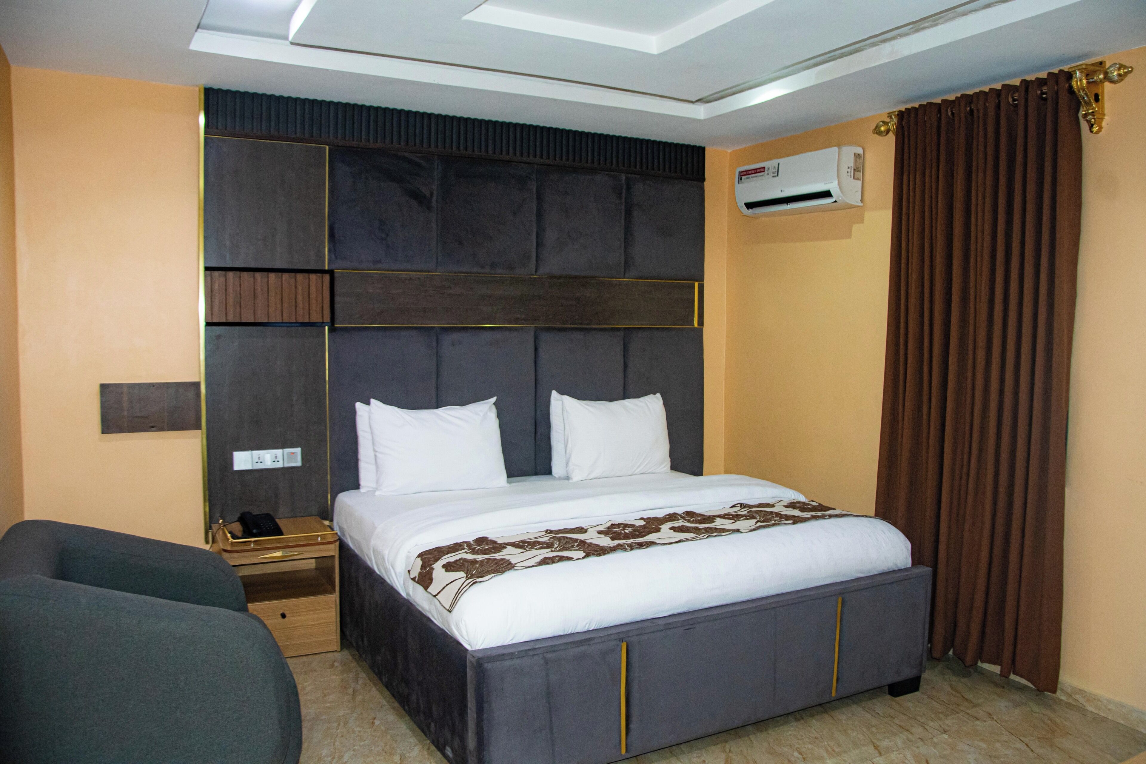 Een hotelkamer met een bed, nachtkastje en een airconditioning.