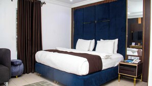 Un dormitorio con una cama grande, una mesita de noche con un teléfono y una silla.